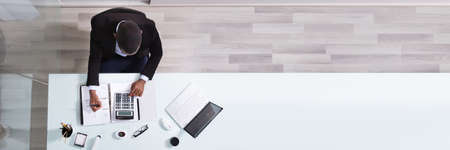 Happy African Businessman Looking At Laptop Calculating Invoice In The Office