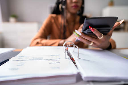 Cropped image of businesswoman calculating tax at desk in officeの写真素材