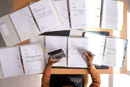 Portrait of confident businesswoman calculating tax at desk in officeの写真素材