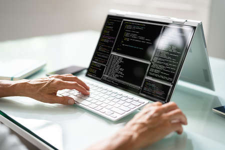 Programmer Or Coder At Office Desk Using Laptopの写真素材