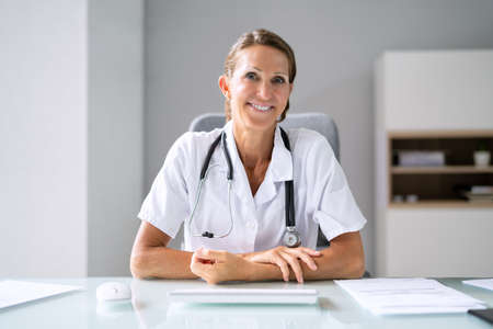 Portrait Of A Happy Female Doctor With Stethoscope On Deskの写真素材