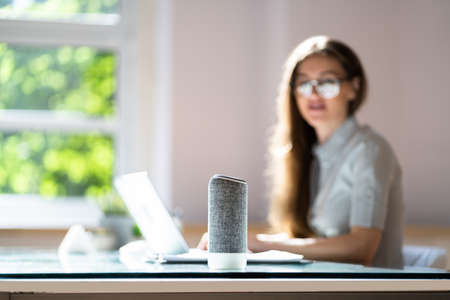 Smiling Young Woman Using Voice Assistant In Officeの写真素材