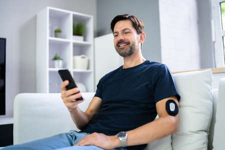 Man Using Continuous Glucose Remote Monitor Diabetes Sensorの写真素材