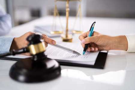 Judge Assisting Client To Sign Legal Document In Courtroomの写真素材