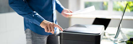 Midsection Side View Of Businessman Pressing Printer's Button In Officeの写真素材