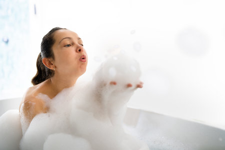 Bathroom Relaxation And Wellbeing. Woman Blowing Soap Foam Bubbles