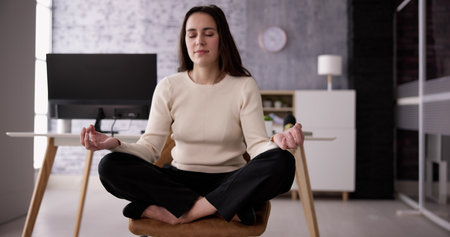 Employee Doing Mental Health Yoga Meditation In Officeの写真素材