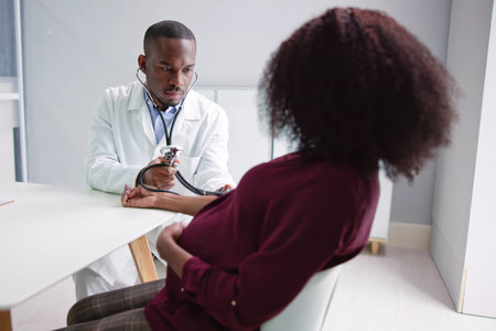 Male Doctor Measuring Blood Pressure Of Pregnant Woman In Clinicの写真素材