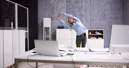 Arms Stretch Exercise Standing Near Desk In Officeの写真素材