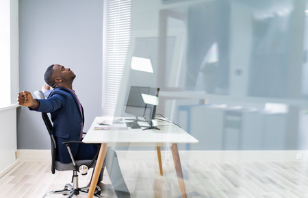 African Man Doing Stretching Exercise At Office Deskの写真素材