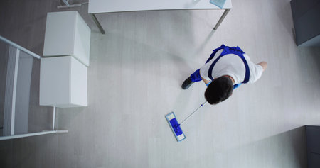 Janitor Cleaning White Desk In Modern Office
