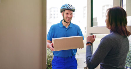 Happy Young Woman Accepting Parcel Box From Delivery Manの写真素材