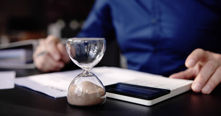 Hourglass On Desk. Running Late With Invoice Or Billの写真素材
