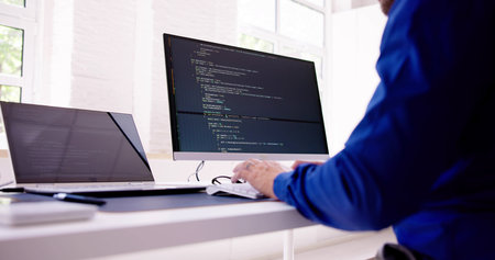 Computer Programmer Writing Program Code On Computer In Office