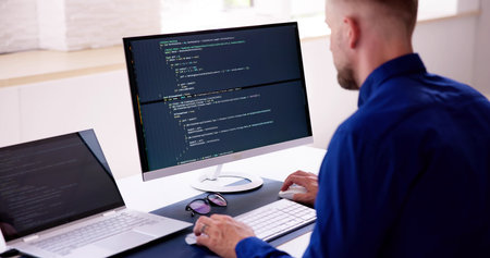 Computer Programmer Writing Program Code On Computer In Officeの写真素材