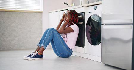 Frustrated Young Woman Sitting On Kitchen Floorの写真素材