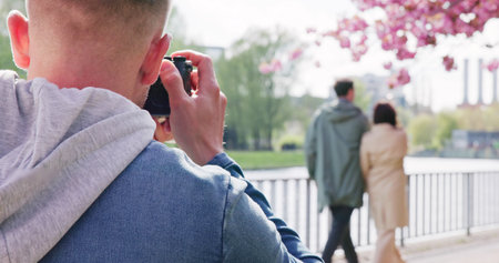Man Paparazzi Photographer Capturing A Photo Suspiciously Of Couple Walking Togetherの写真素材