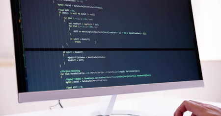 Computer Programmer Writing Program Code On Computer In Office