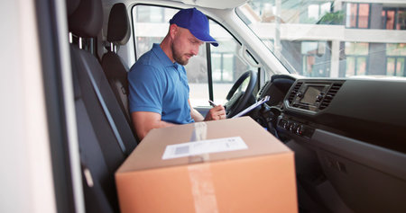 Young Delivery Man Removing Cardboard Box From Truckの写真素材