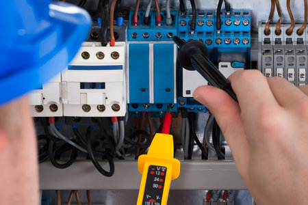 Male Electrician Examining Fusebox With Voltage Tester