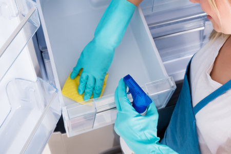 High Angle View Of Young Woman Cleaning Empty Refrigeratorの写真素材