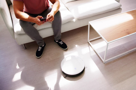 Home Robot Cleaner Doing Housework Near Sofaの写真素材