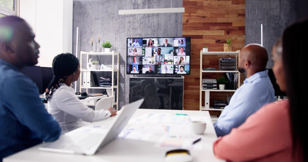 Group Of Businesspeople Having Video Conference With Another Business Team In Office