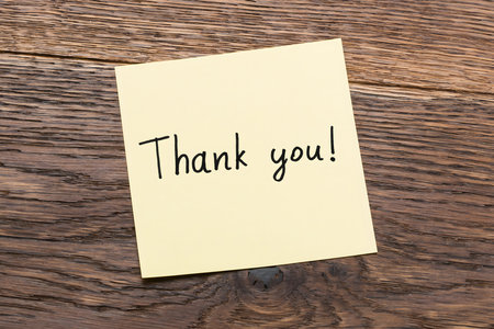 High Angle View Of Text Thank You On Post Note At Wooden Deskの写真素材