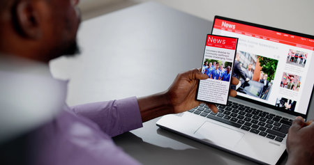 Watching Online News Article On Mobile Phone And Laptop. Electronic Newspaperの写真素材