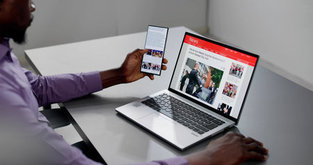 Watching Online News Article On Mobile Phone And Laptop. Electronic Newspaperの写真素材