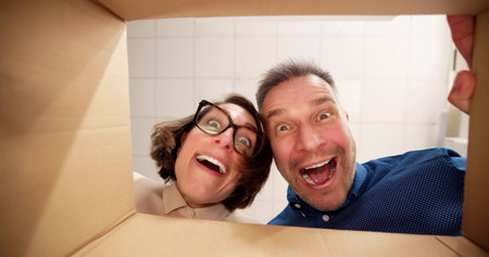 Low Section View Of A Young Happy Couple Looking Inside Cardboard Boxの写真素材