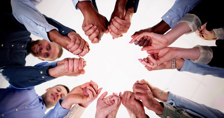 Directly Below Creative Business Team Stacking Hands While Standing In Huddle