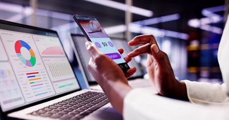 African American woman using smartphone app to donate money online, supporting charities and...