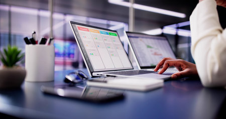 Focused African American woman using laptop to manage business schedule, calendar, and Gantt chart...