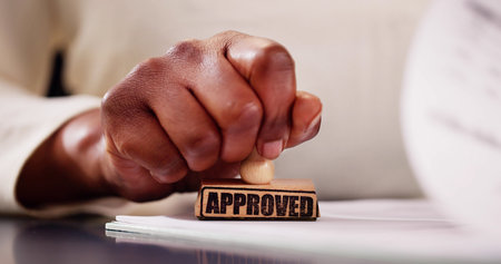 Notary Public with Afro-American hands approving a legal document in a black and white office using a stamper.の写真素材