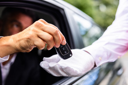 Luxury chauffeur service at a hotel: a businessperson's hand giving car key to valet in the city,...