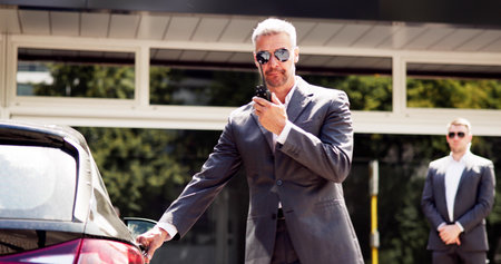 Professional bodyguards opening luxury car door for mature businessman outside corporate event - VIP...