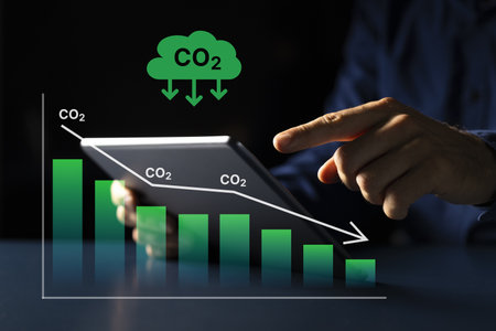 Young Caucasian man using tablet computer to analyze sustainable investment options in carbon credit...