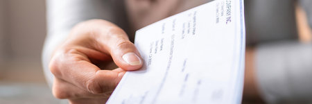 Hand giving paycheck, check, cheque in transaction conceptの写真素材