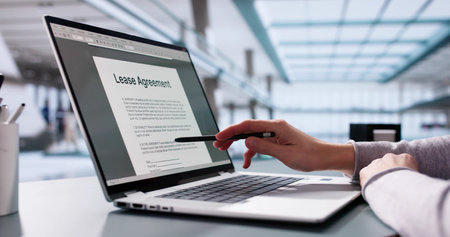 Female businesswoman reviewing leasing contract on laptop, considering property investment.の写真素材