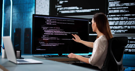 Young woman coding at desk in office as web developer.の写真素材
