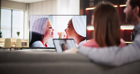 Man watching internet streaming from connected tablet to television at home.