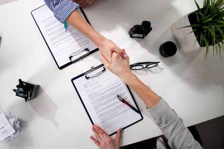 Successful Businesswomen Celebrate New Contract Signing in Modern Officeの写真素材