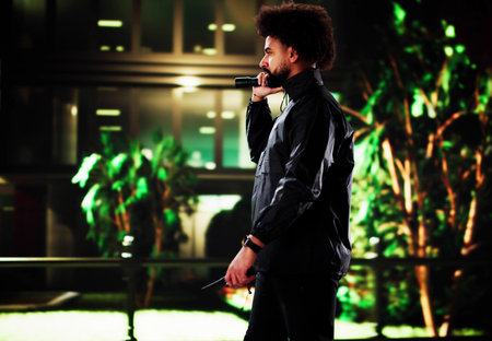 Nighttime Security Guard Patrolling Building Perimeter with Flashlight in City.の写真素材