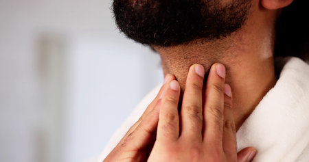 The doctor examined the man's sore throat and thyroid.の写真素材