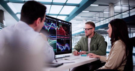 Financial Analysts Analyzing Stock Charts On Computer Screens In Office Setting.の写真素材