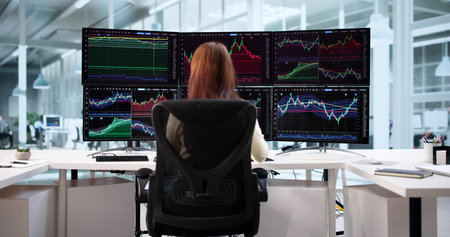 Professional Businesswoman Analyzing Stock Market Trends On Computer Screens In Office.