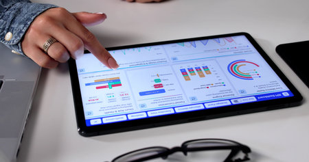 Female Business Analyst Pointing At KPI Dashboard On Tablet Computerの写真素材
