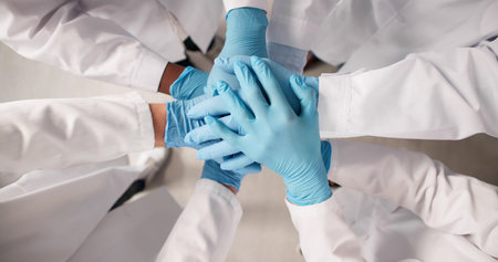 Medical Team Shows Unity With Stacked Hands In Hospital Setting. Group Of Diverse Professionals Collaborateの写真素材