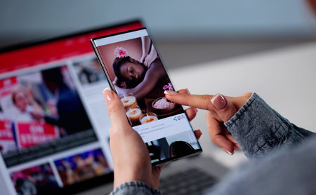 Woman Is Checking The Latest Social Media Updates Online. She Is Scrolling Through News Feeds On Her Smartphone Appの写真素材